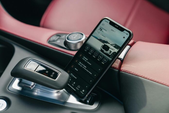 Smartphone menampilkan antarmuka mobil di konsol mobil.